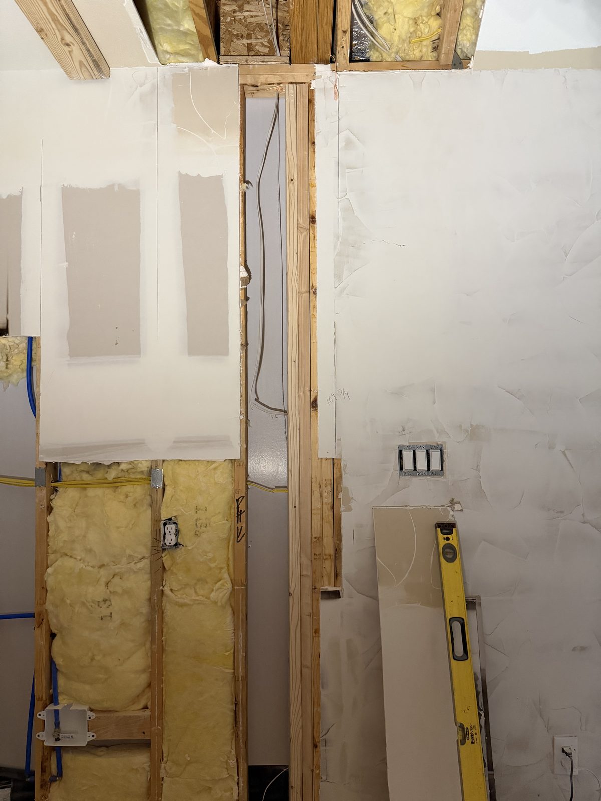 Opened kitchen wall during a remodel in Murphy, TX, showing studs, insulation, new plumbing and electrical boxes