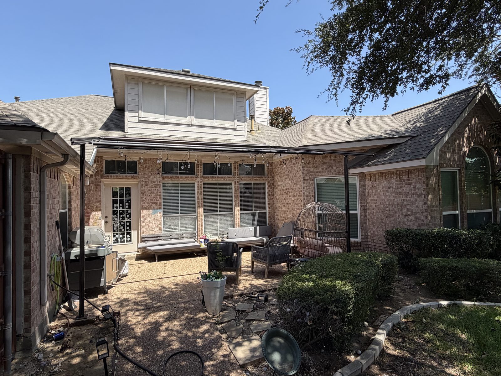 Existing brick courtyard with trees and patio before construction in Richardson, TX