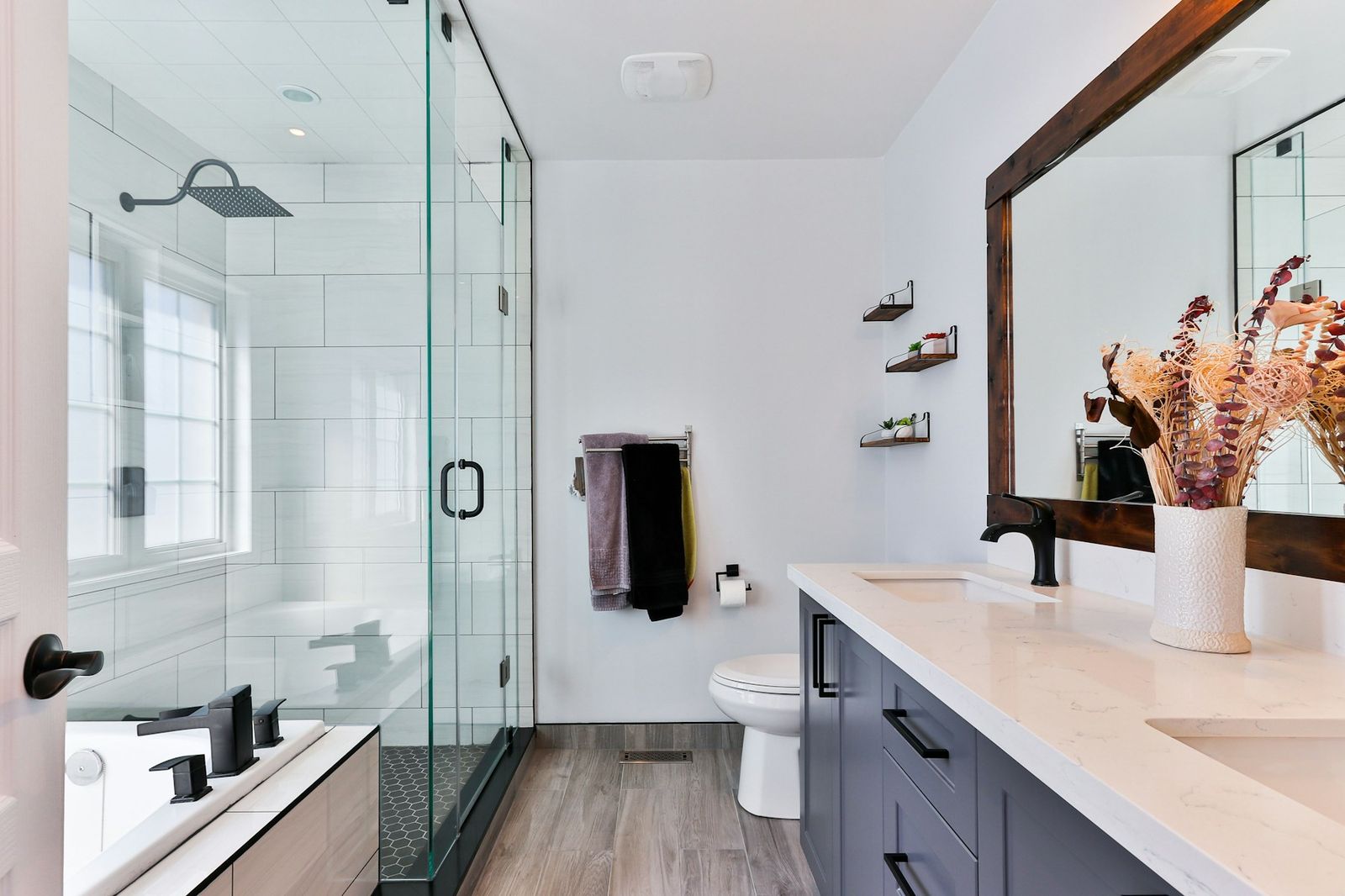 Modern bathroom with glass walk-in shower, soaking tub and navy vanity
