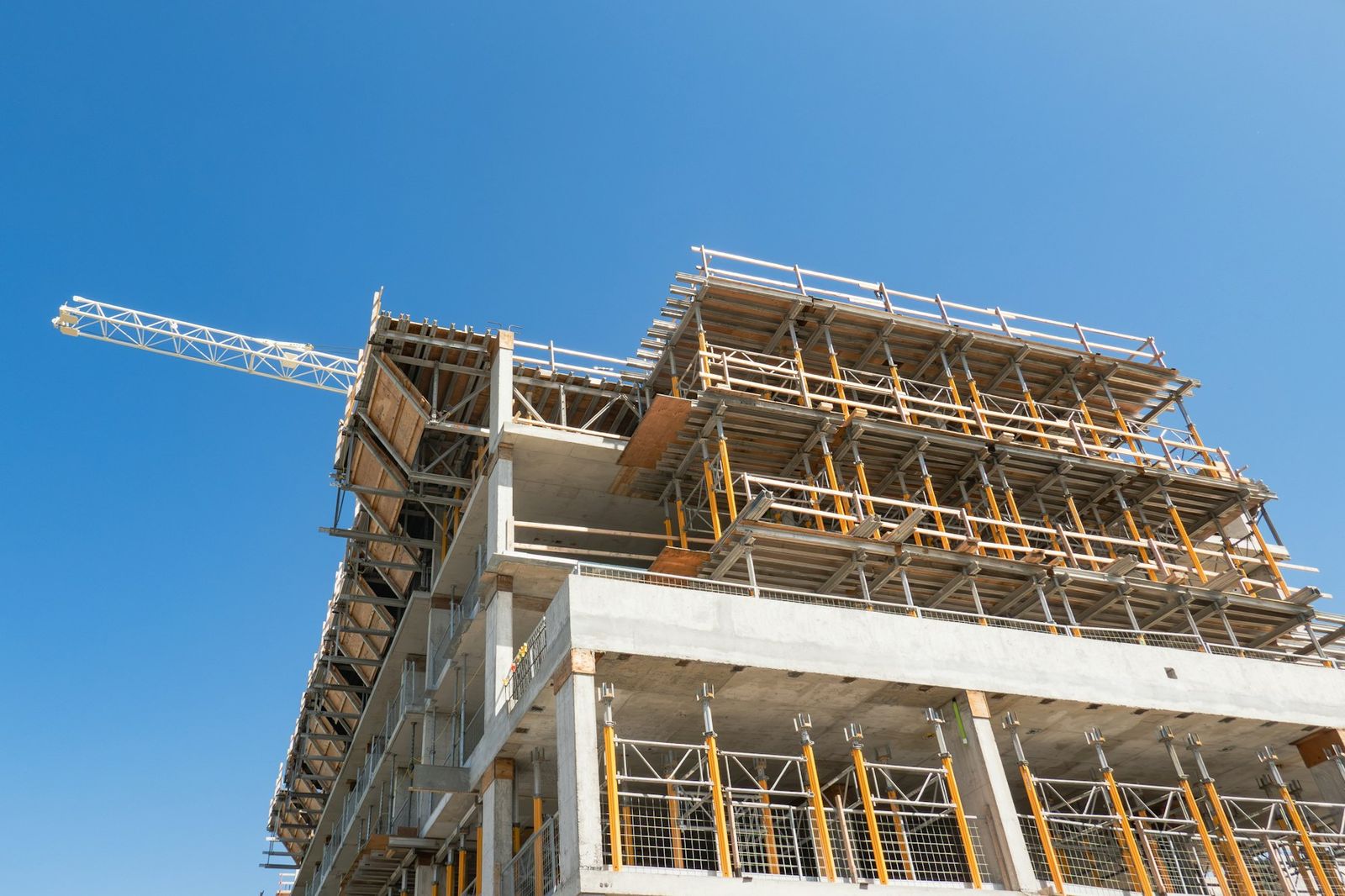 Multi-story concrete building under construction with a tower crane