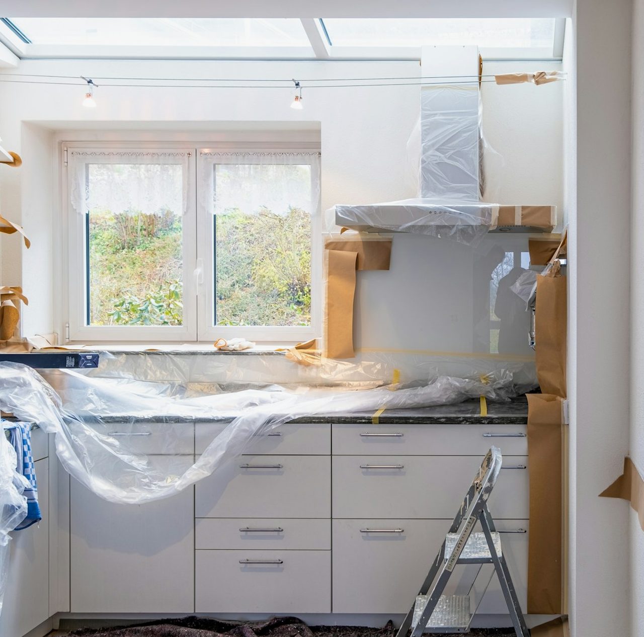Kitchen being prepared for renovation with protective sheeting and a ladder